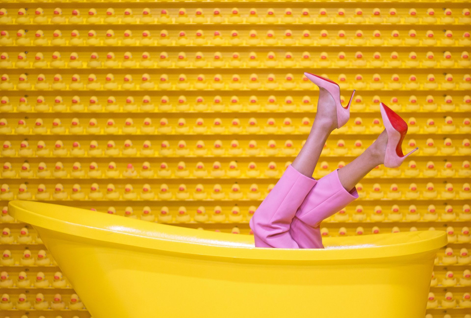 A woman is sitting in a yellow bathtub with her legs up.