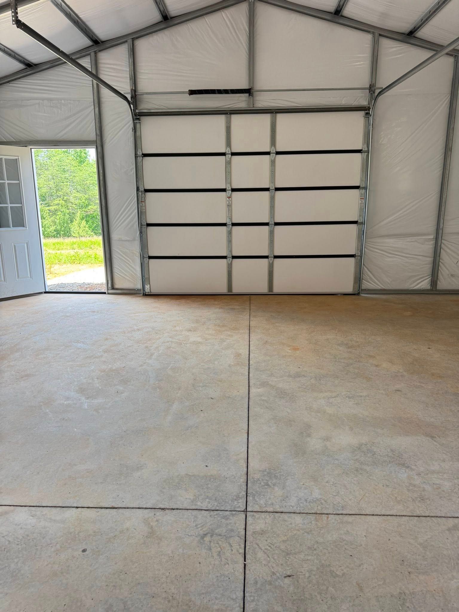 Empty garage interior with a concrete floor and a closed white roll-up door at the back.