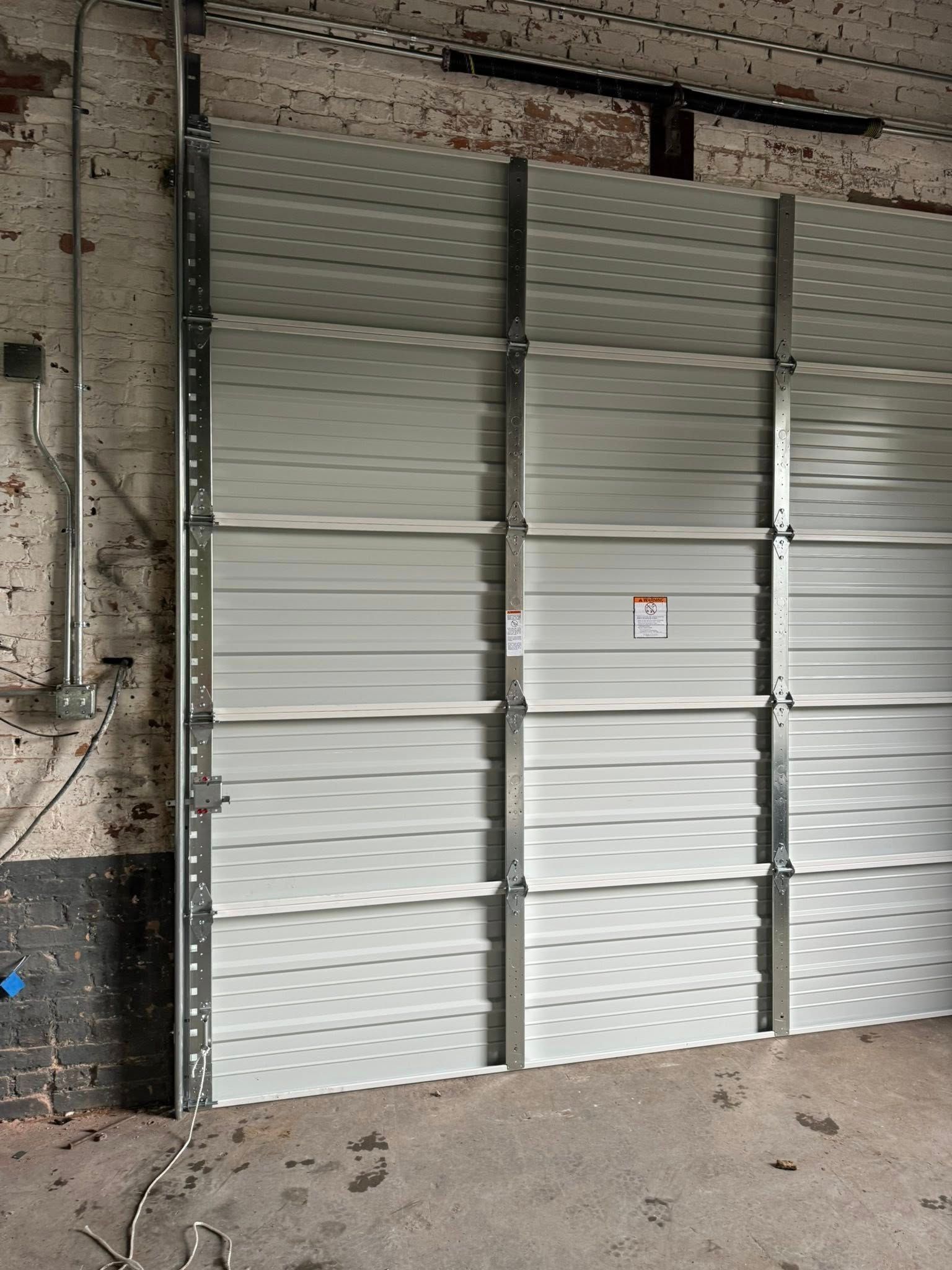 Closed white corrugated metal garage doors in an industrial warehouse setting