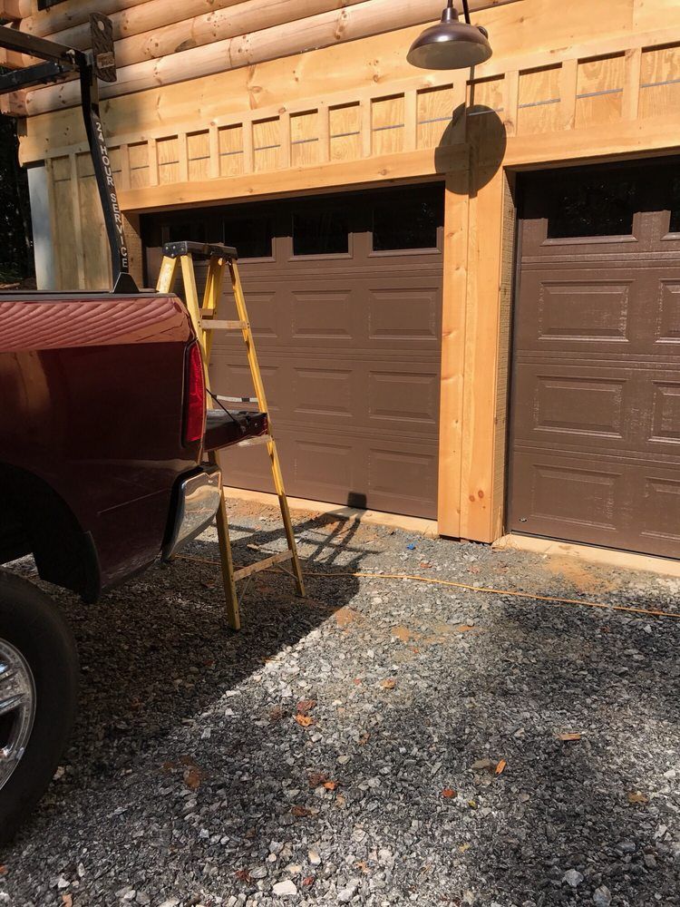 Pickup truck parked beside a wooden garage under construction, with a ladder on gravel.