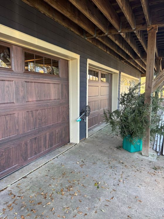 Covered outdoor walkway with brown doors, a blue hand truck, and a potted plant