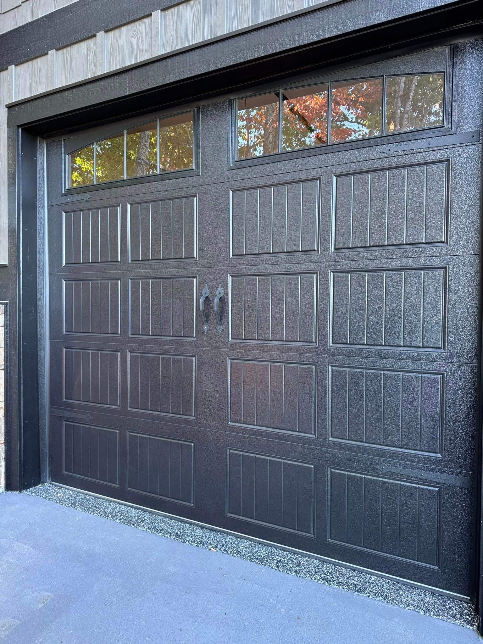 Black paneled garage door with narrow windows at the top, viewed from outside.
