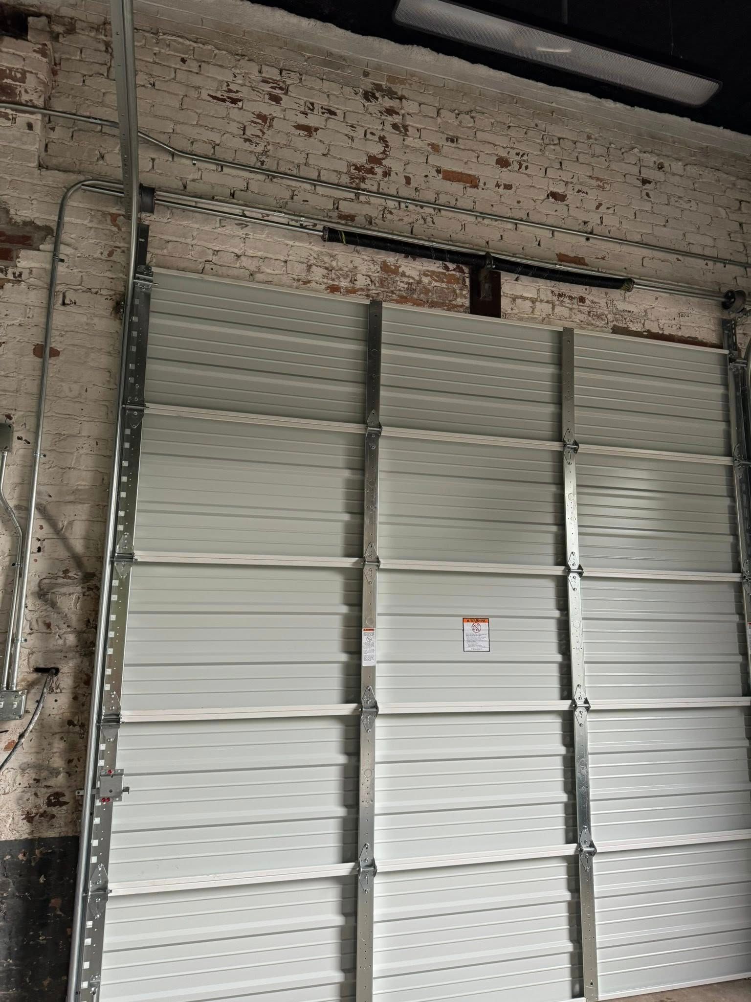 Stacked white panels blocking a storefront entrance, with a weathered brick wall on the left.