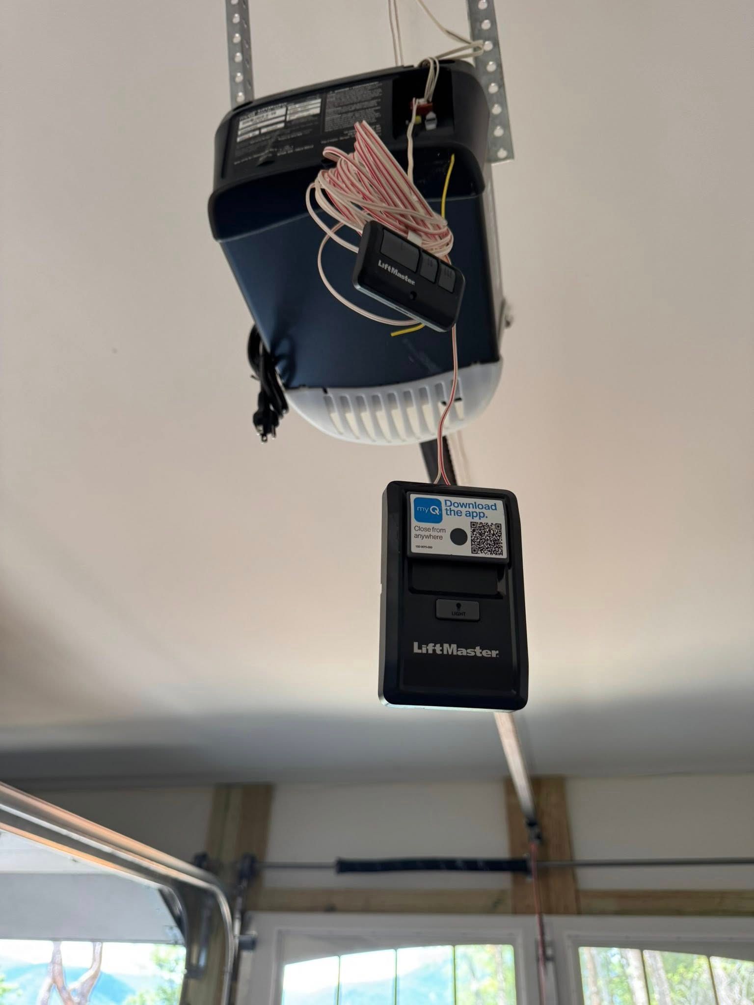 Garage door opener motor mounted on the ceiling with a hanging remote