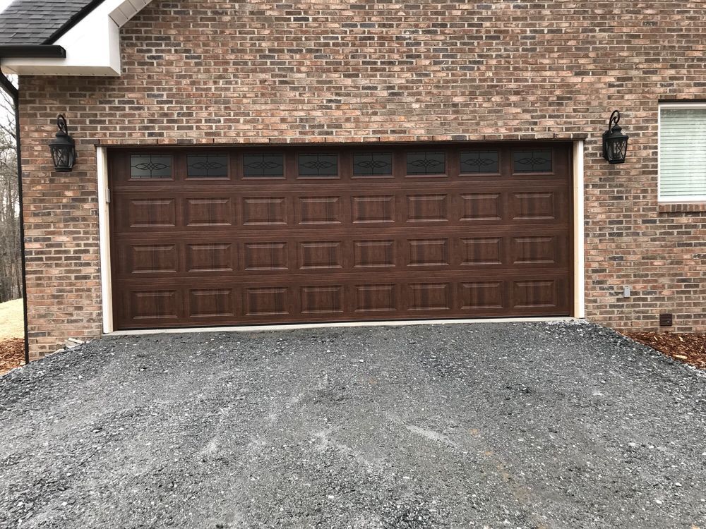 Brick house facade with a dark brown double garage door and a gravel driveway