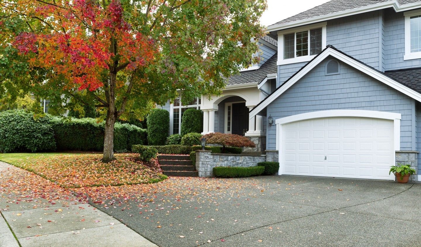 Suburban house with a two-car garage and a tree with red-orange autumn leaves in the front yard