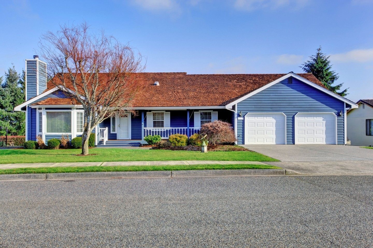 Single-story blue house with red roof, white trim, and a two-car garage behind a gravel driveway