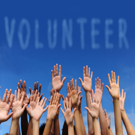 A man is holding a cardboard sign that says volunteer.