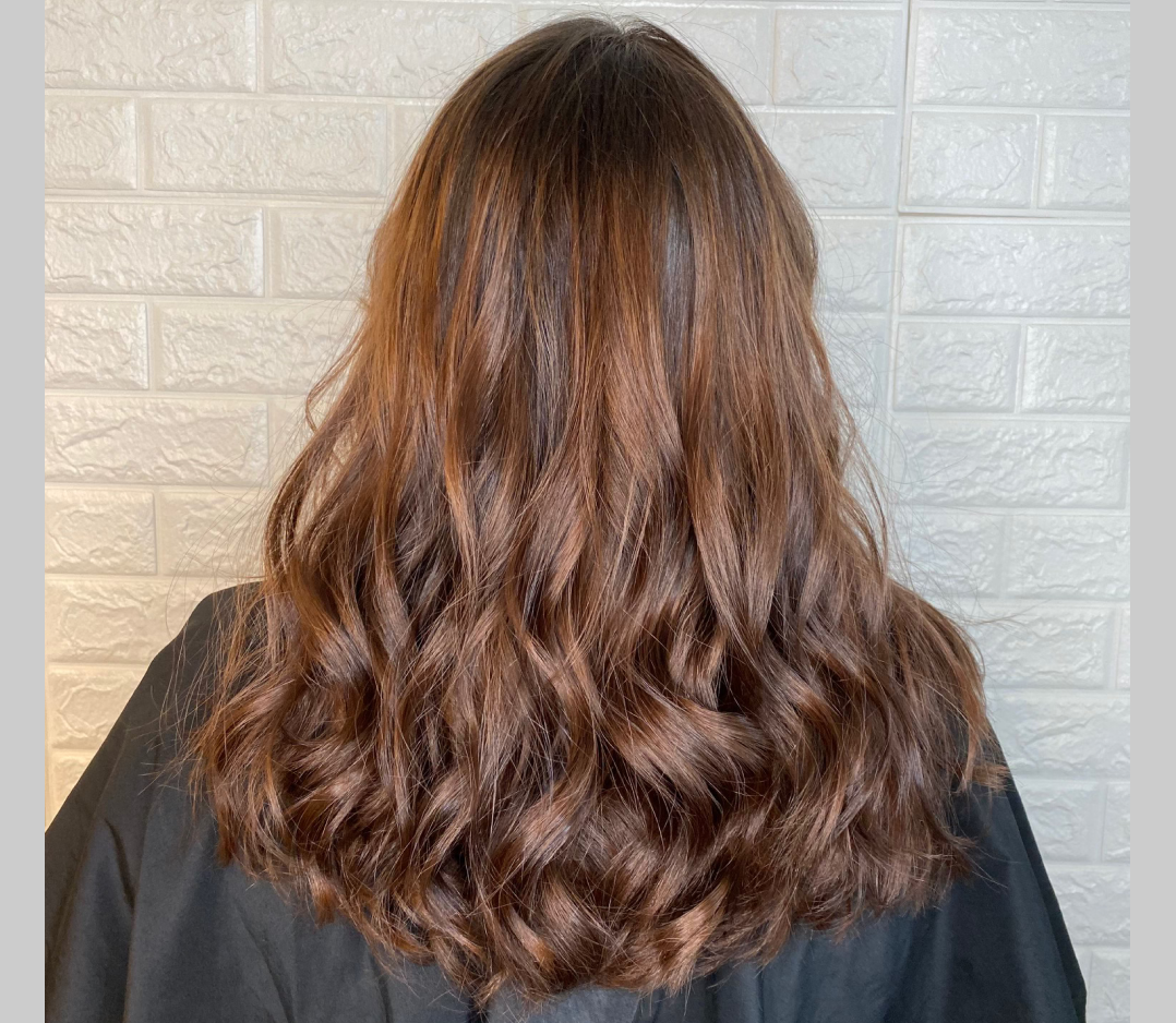 Woman's hair after coloring and it is brown with pretty highlights and soft curls.