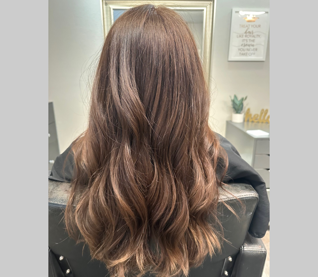After picture of a woman with long brown hair with beautiful highlights and soft waves.