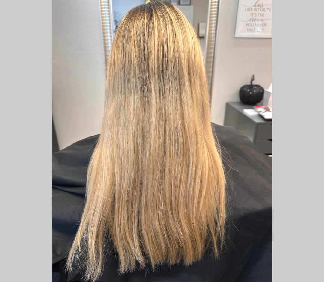 Before picture of a woman with long blond hair with bad color highlights.