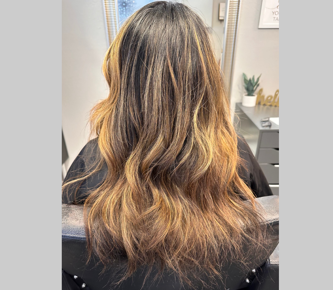 Before picture of a woman's hair with lots of highlights on brown hair.