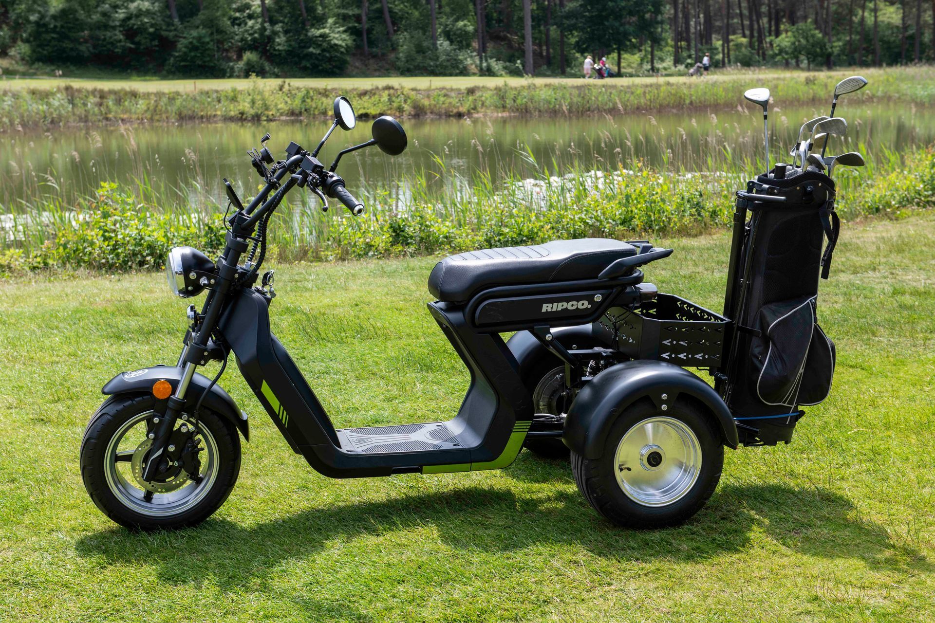 Golfkarretje op een golfbaan. Zwart-groen scootertje met een golftas, op het gras met een golfbal en tee.