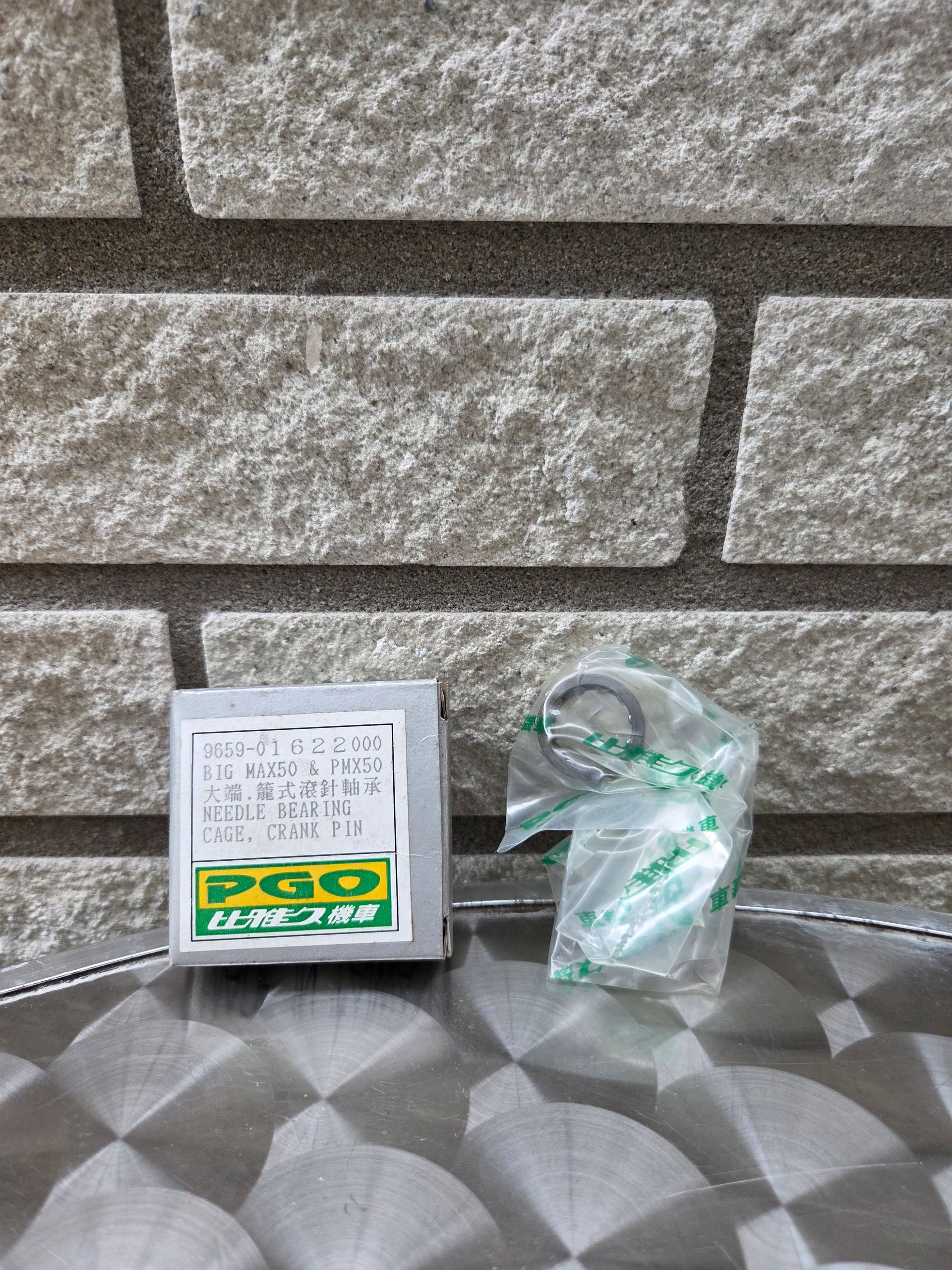Een klein doosje en een in doorzichtig plastic verpakt voorwerp op een tafel met een patroon voor een stenen muur.