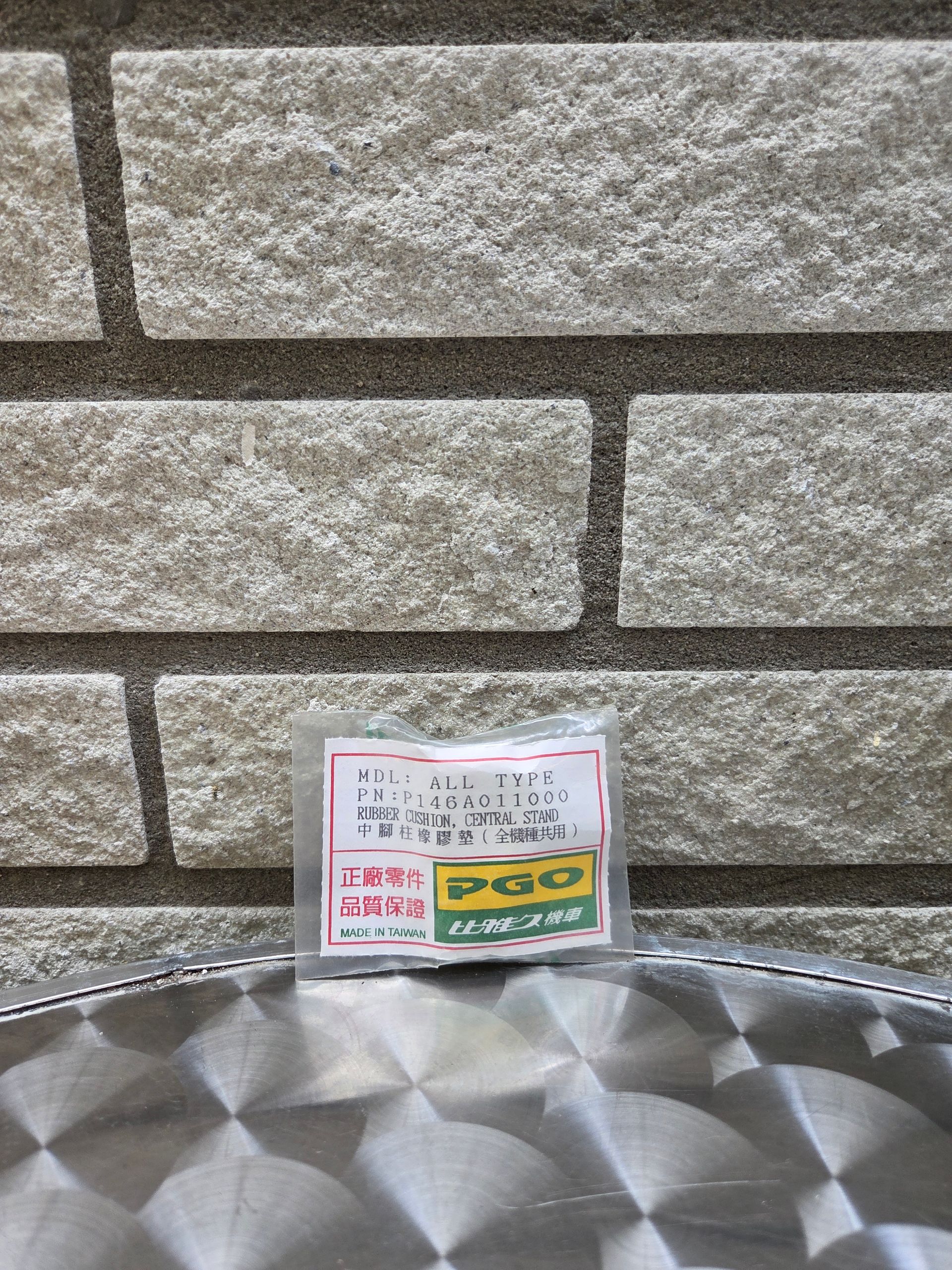 Klein verpakt artikel met Japans etiket op een metalen dienblad tegen een stenen muur.