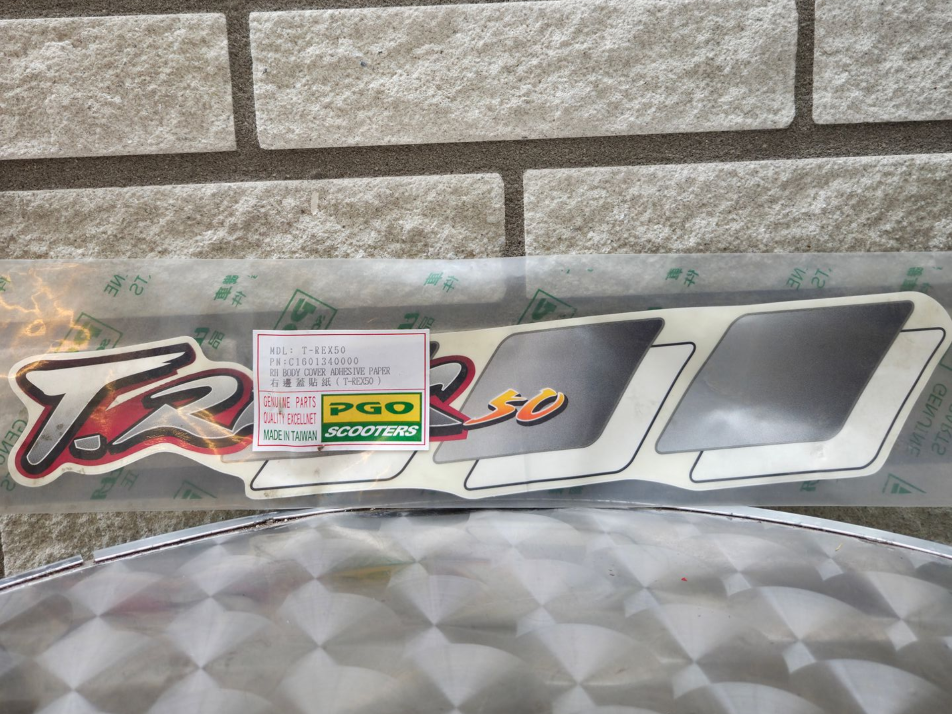 Decoratieve autosticker in TRD-stijl op een stenen muur, met daaronder een grijs, gestructureerd kussen.