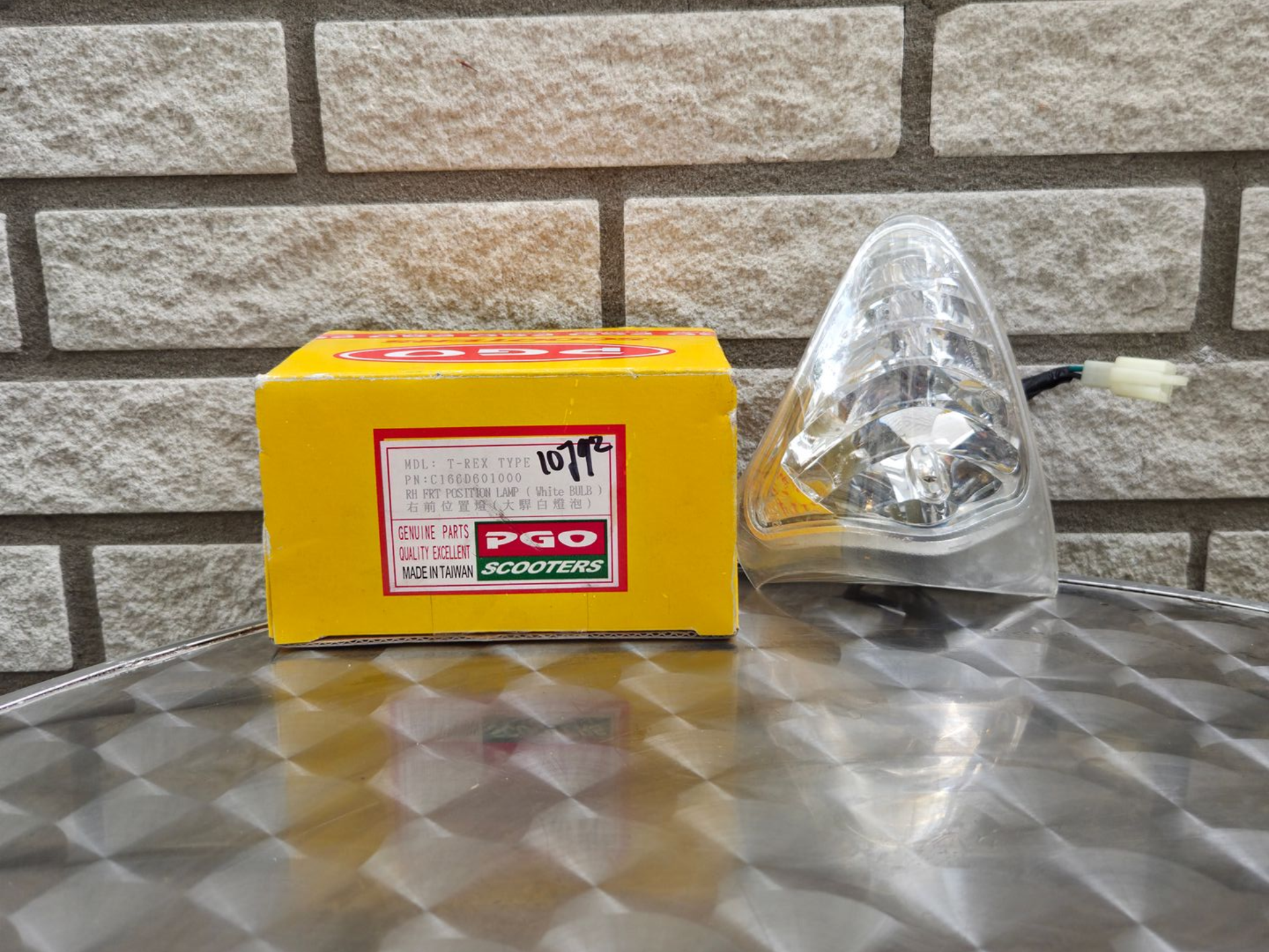 Gele P90-doos naast een doorzichtige plastic kegel op een metalen ondergrond tegen een bakstenen muur.