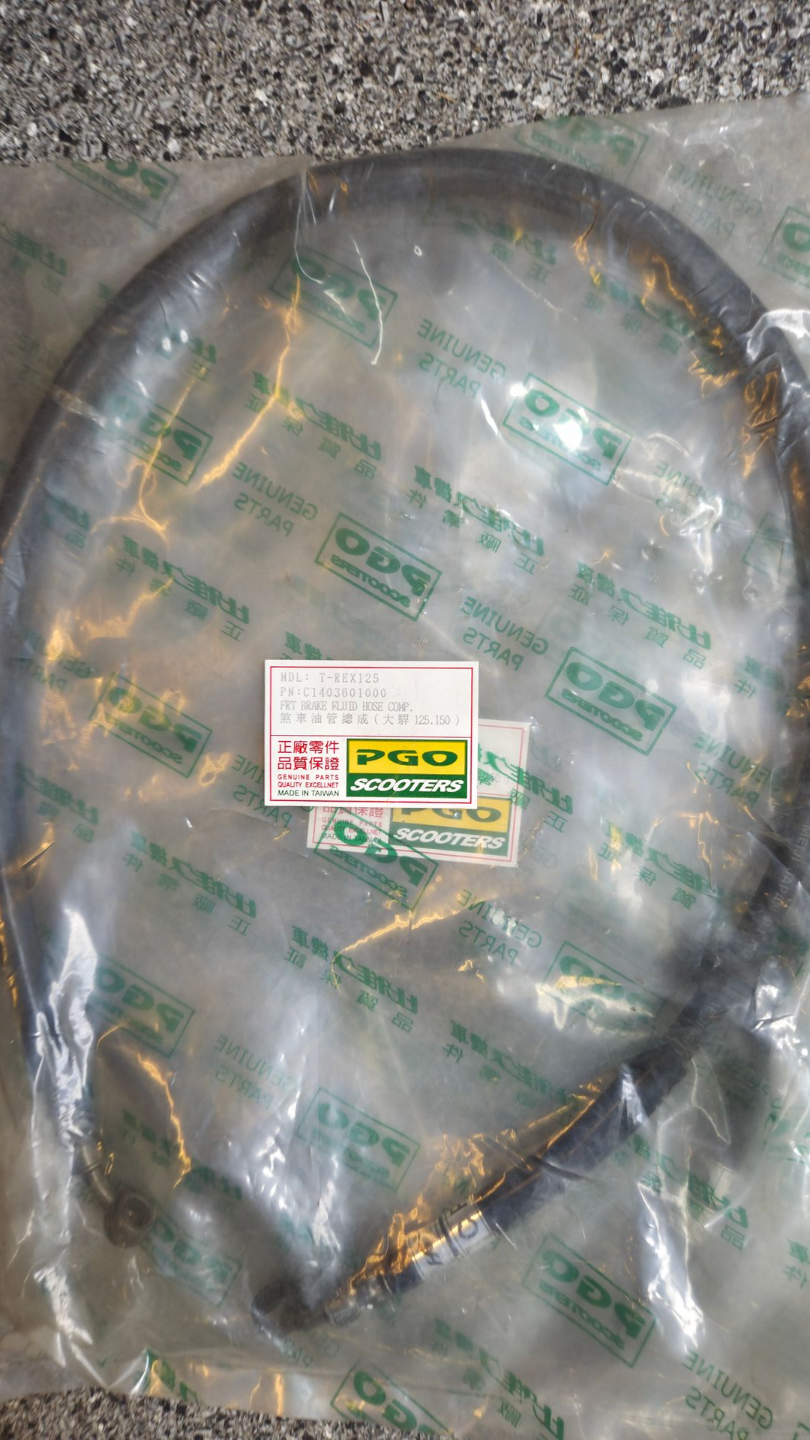 Een in plastic verpakte zwarte band of slangrol op grind, met een klein etiketje erop.