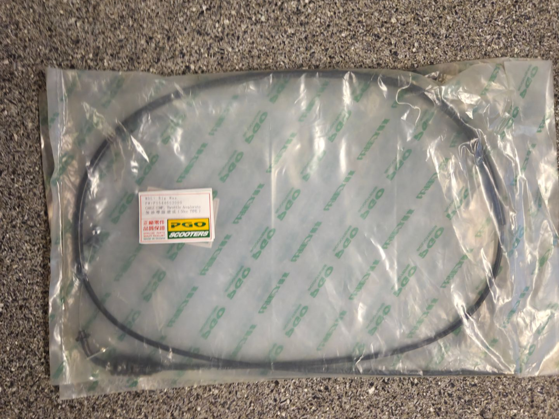 Een opgerolde zwarte kabel, verpakt in een doorzichtige plastic zak, ligt op een gestructureerd oppervlak.
