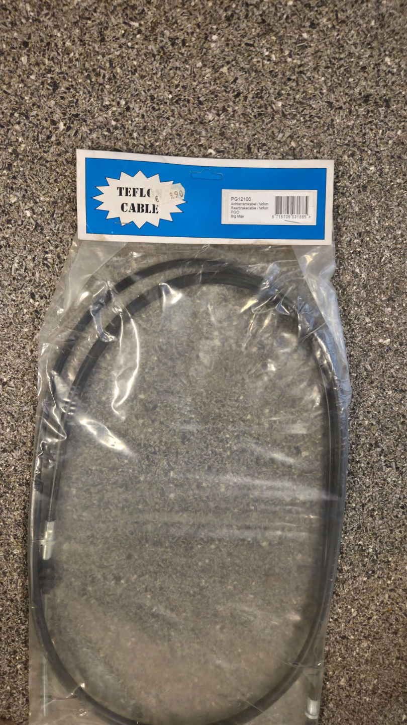 Een doorzichtige plastic zak met een zwarte ovale kabel op een blauw-wit label, liggend op het tapijt.