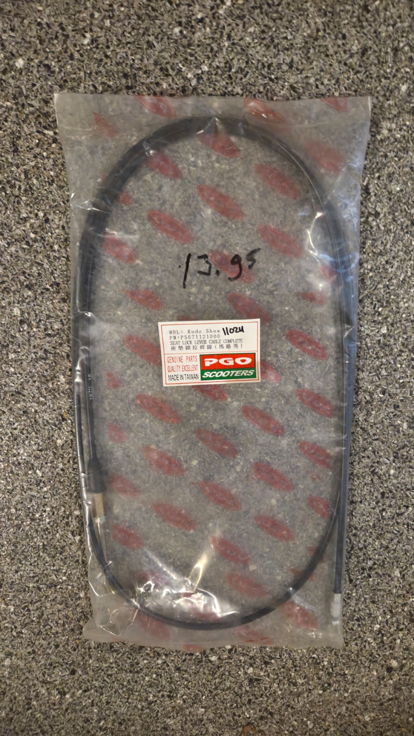 Doorzichtige plastic zak met een zwarte kabel of riem op een grijze ondergrond, voorzien van een rood-witte sticker.