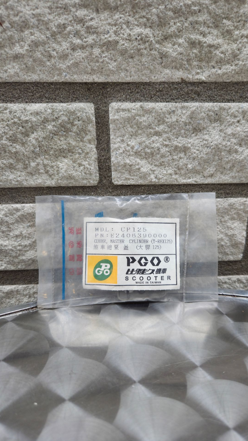 Klein, transparant doosje met een etiket en een kleurrijk logo op een grijs, patroonrijk oppervlak voor een stenen muur.