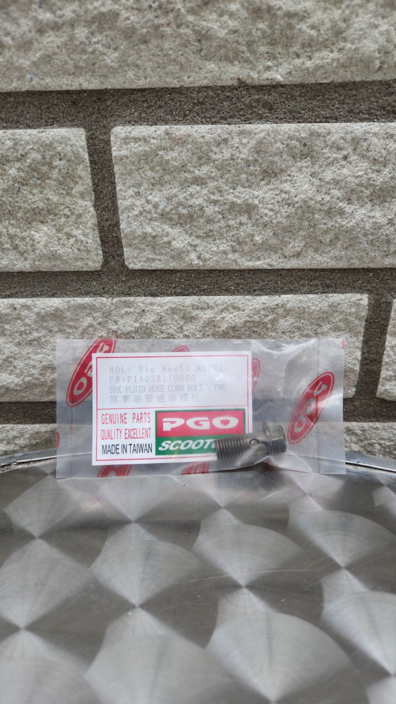 Een kleine verpakking met PGO-logo op een tafelblad met patroon, tegen een bakstenen muur.