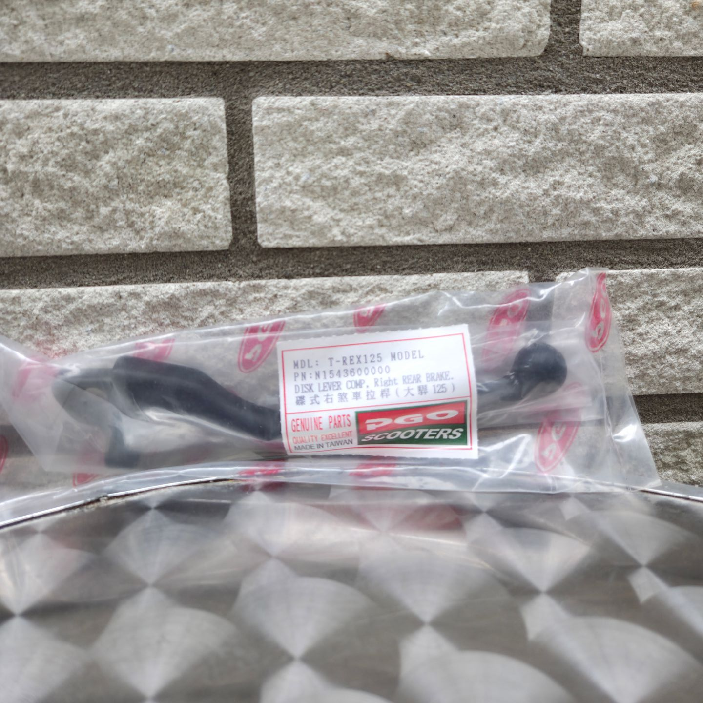 Een in plastic verpakte zwarte gereedschapset ligt op een ondergrond met een patroon voor een stenen muur.