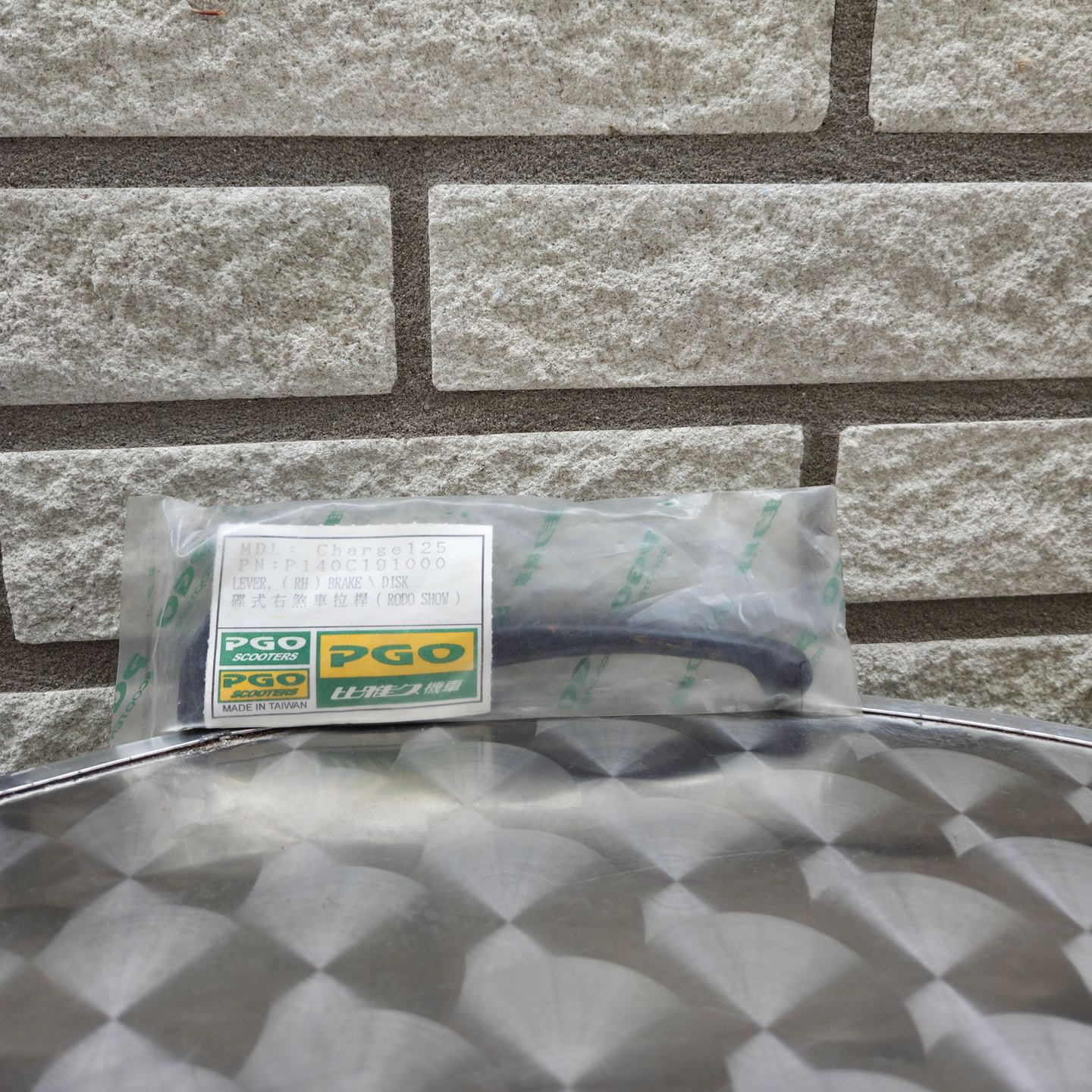 Doorzichtige plastic zak met een PGO-label op een grijs, patroonrijk oppervlak tegen een stenen muur.