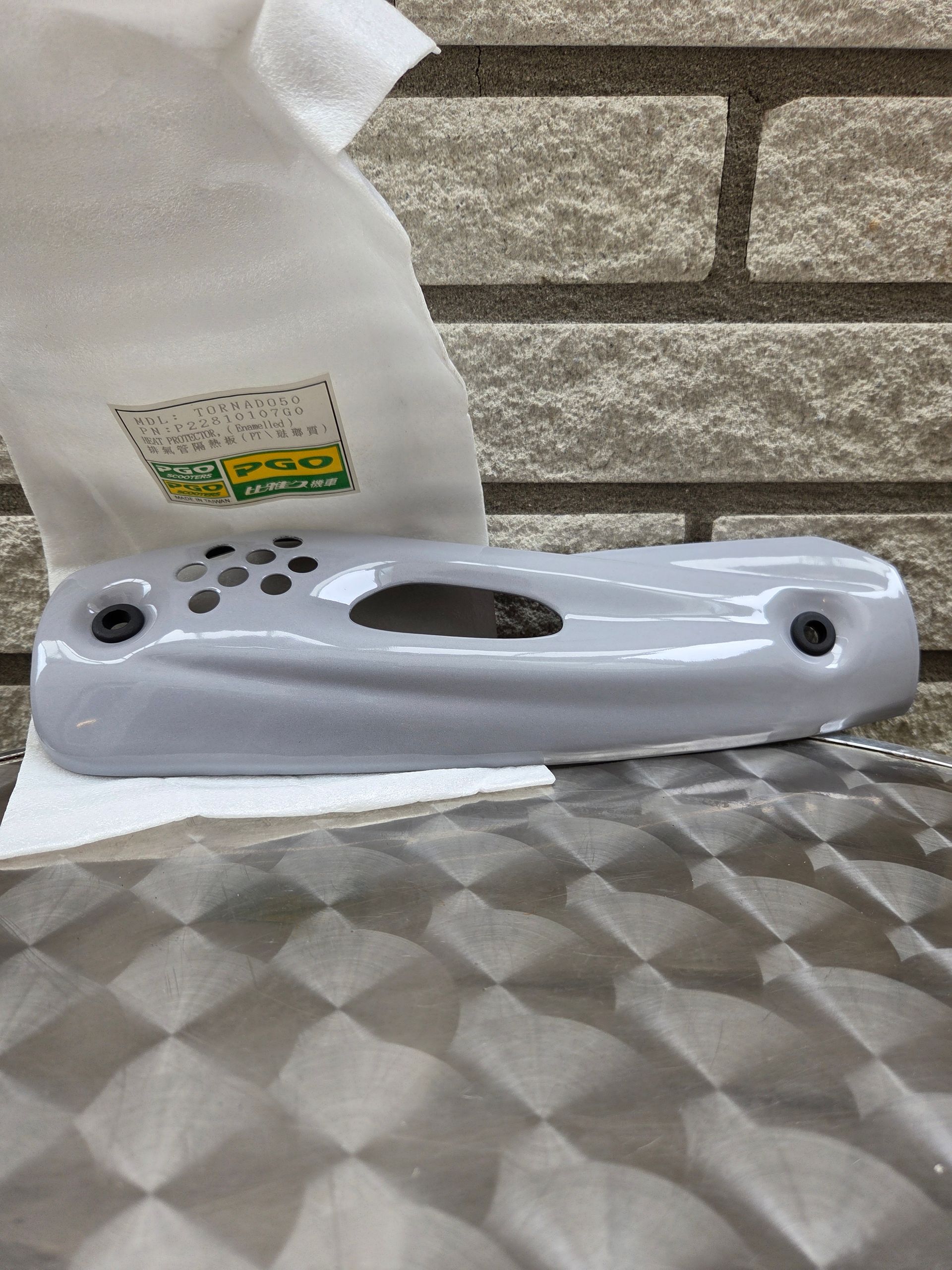 Wit, draagbaar plastic apparaat op een ondergrond met patroon, met een tissue en een bakstenen muur op de achtergrond.