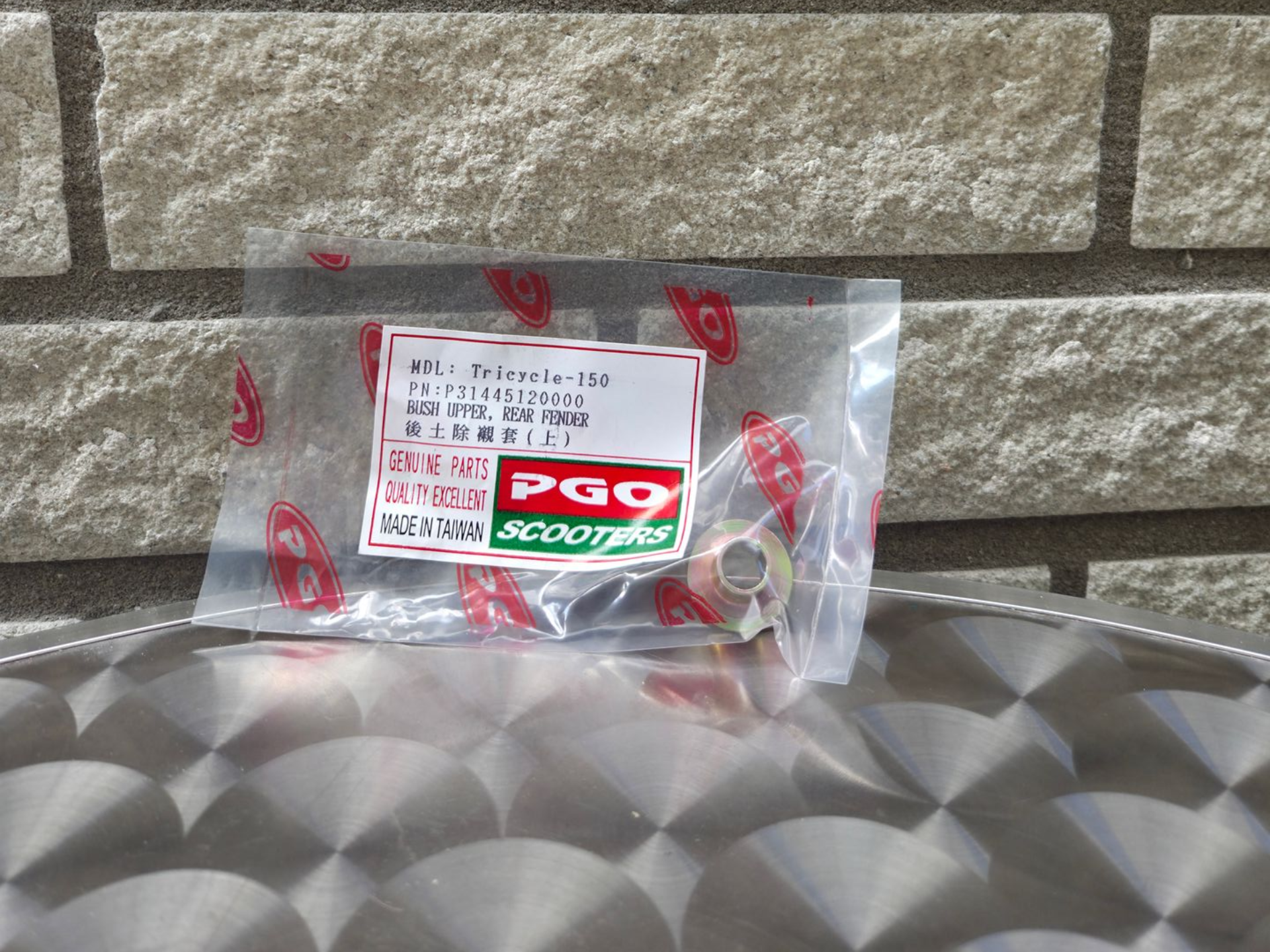 Een doorzichtige plastic zak met een etiket van een voedselverpakking erop, op een metalen ondergrond met structuur, tegen een stenen muur.