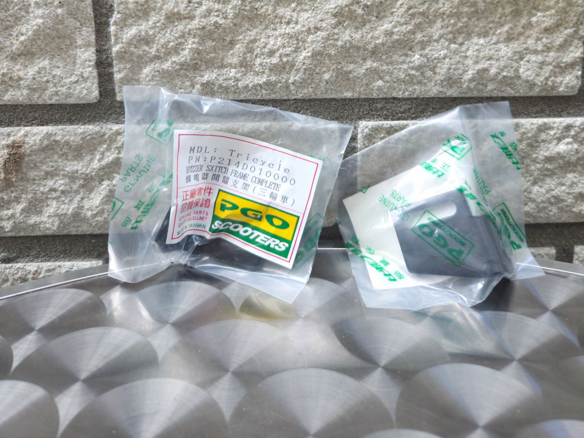 Twee kleine, doorzichtige plastic zakjes met groene etiketten op een zilverkleurige, gewatteerde ondergrond.