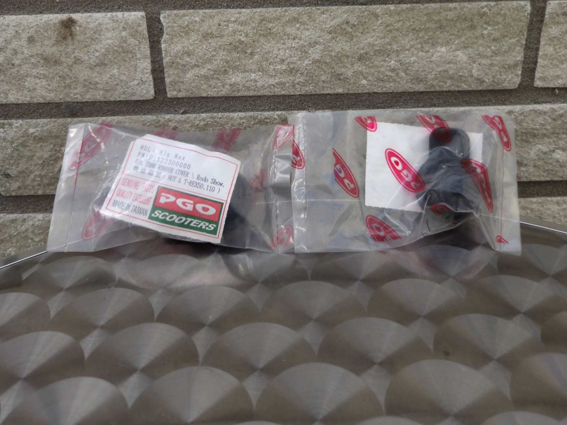 Twee kleine POG-scooters in doorzichtige plastic zakken op een ondergrond met patroon tegen een bakstenen muur.