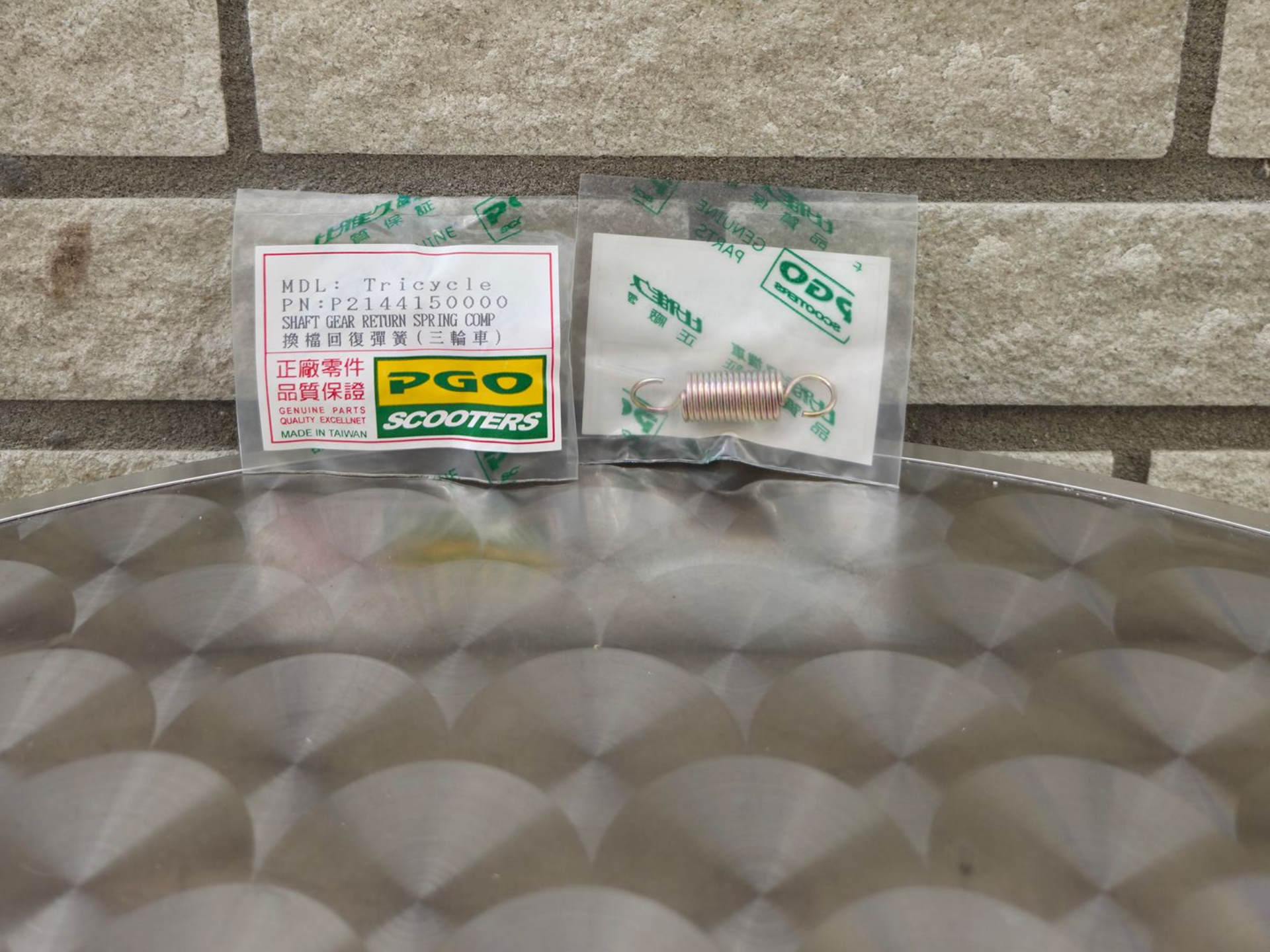 Twee kleine verpakte artikelen met Japanse etiketten op een metalen tafel tegen een stenen muur.