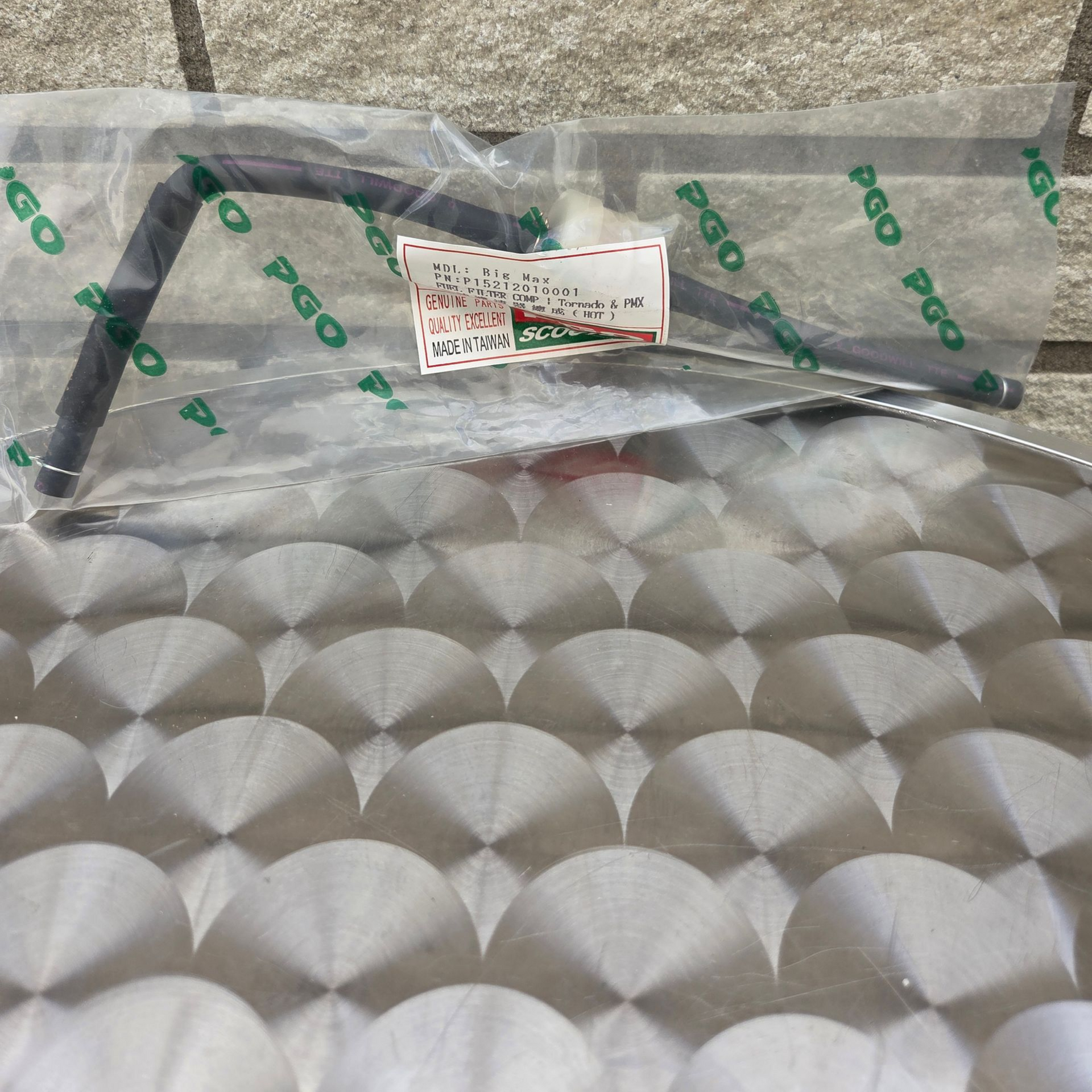 Doorzichtige, in plastic verpakte, gewatteerde zilverkleurige matrasbeschermer op een grijze ondergrond