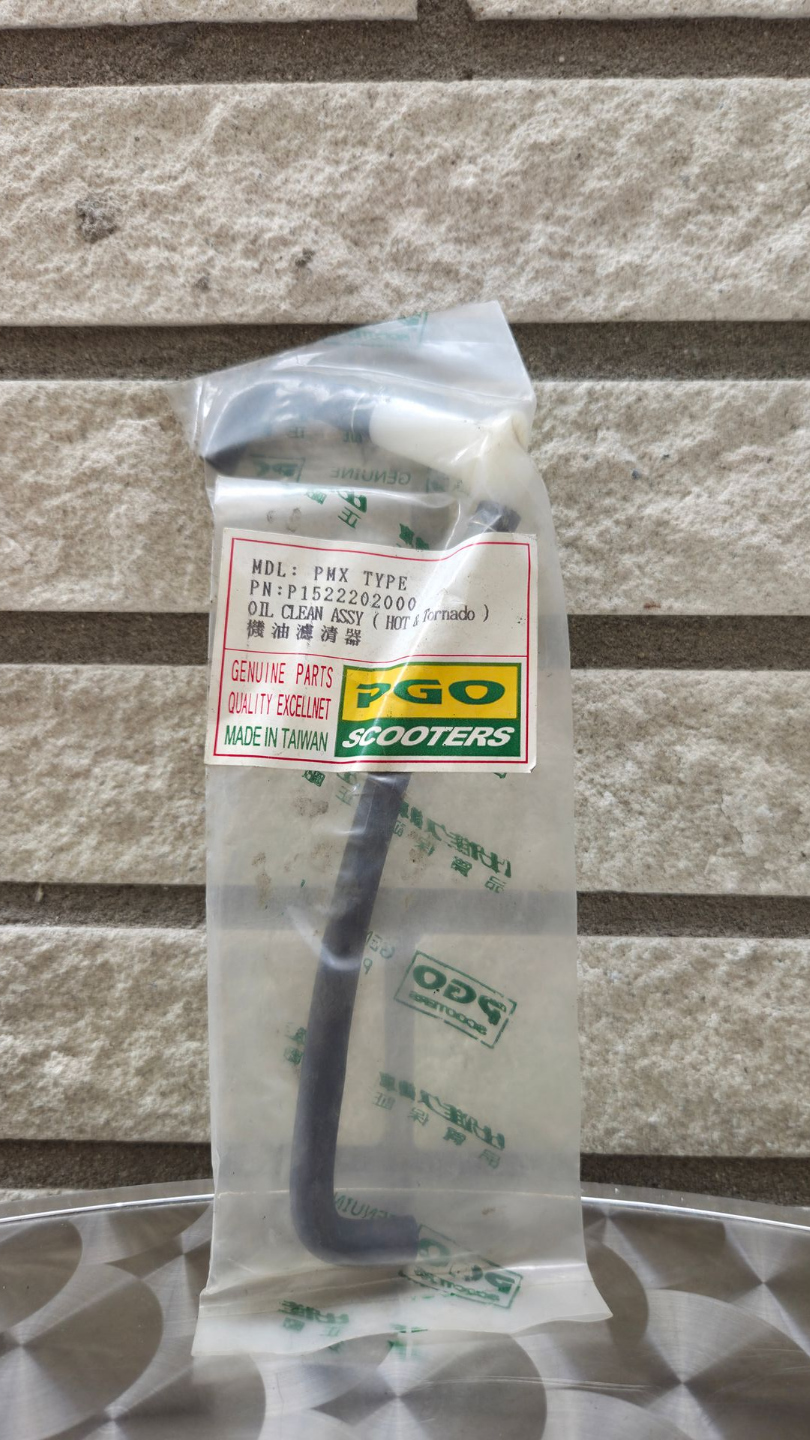 Een doorzichtige plastic zak met een klein zwart gereedschapje en een Japans etiket, tegen een stenen muur.