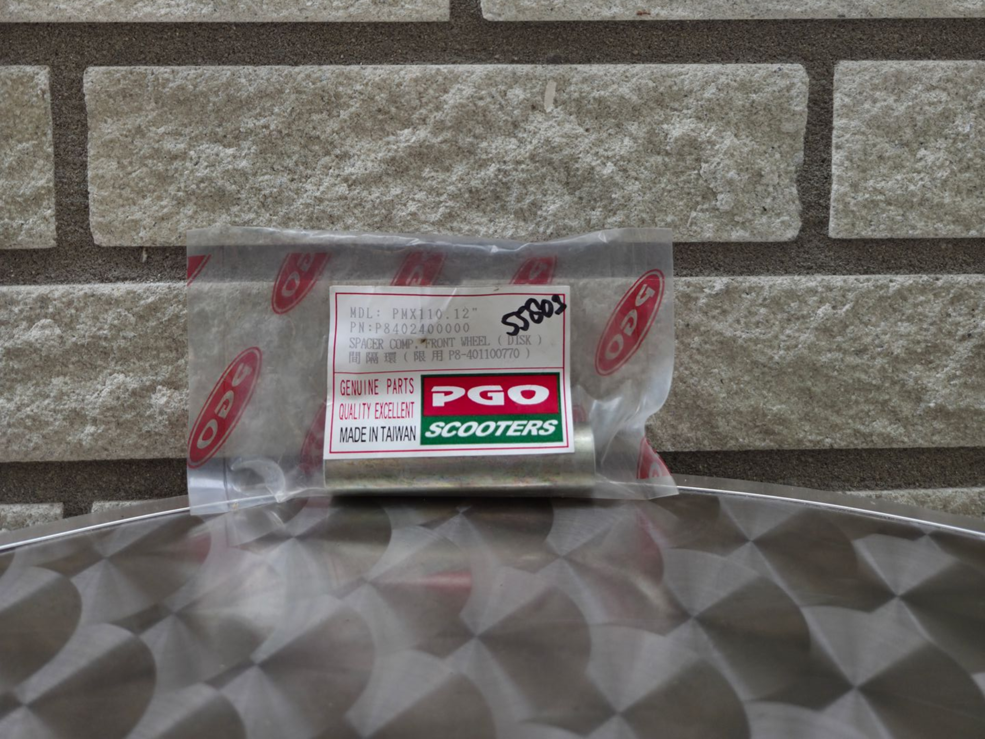 Pakket met PGO-accessoires op een tafel tegen een stenen muur.