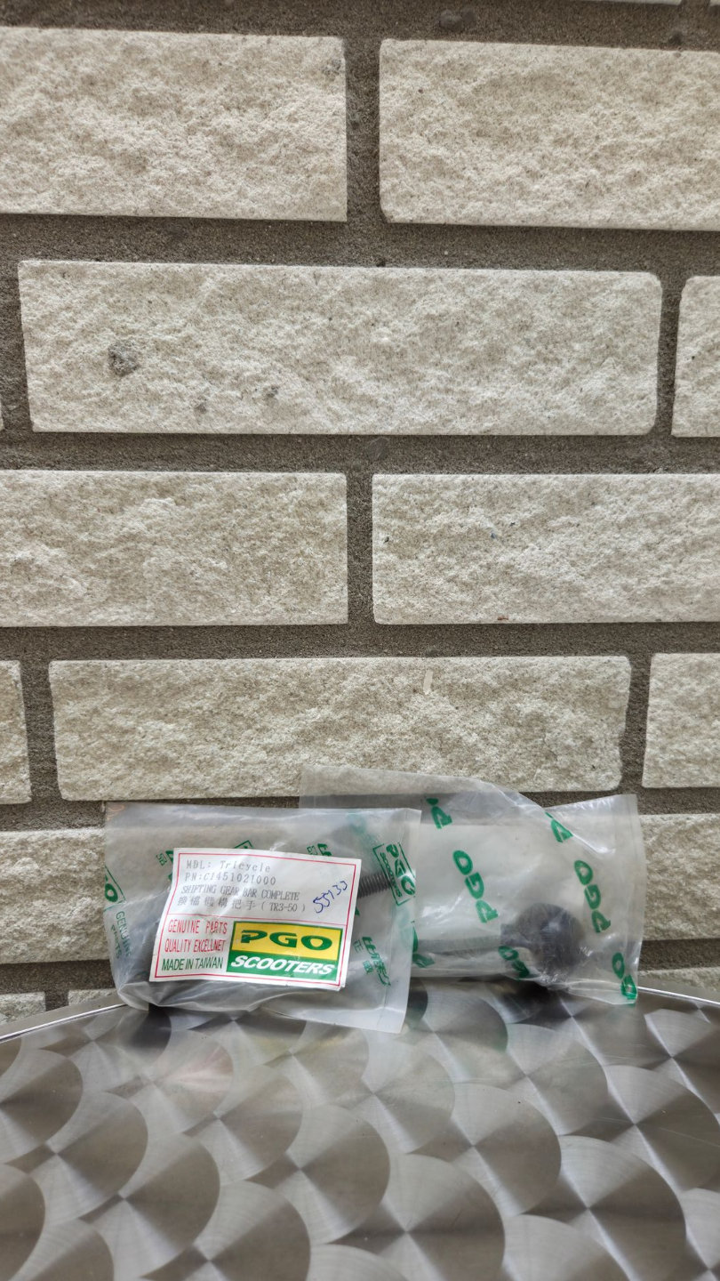 Een klein plastic pakketje en een kabel op een oppervlak met patroon tegen een bakstenen muur.