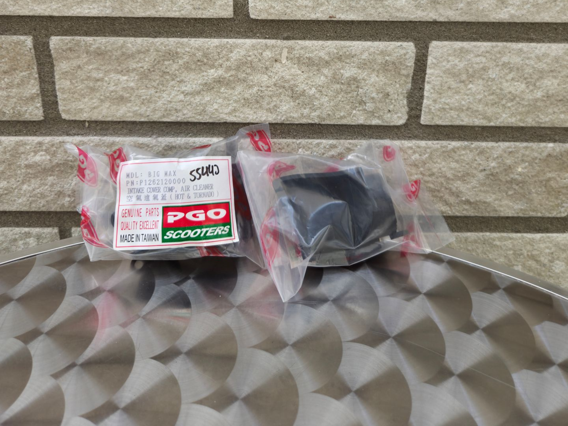 Twee verpakte artikelen op een oppervlak met een patroon voor een stenen muur, waarvan er één is gemerkt met 'POO sticker remover'.