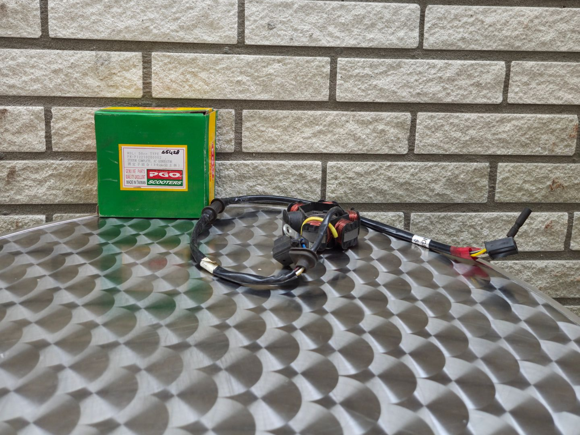 Groene container en zwarte kabelboom op een metalen tafel tegen een bakstenen muur.