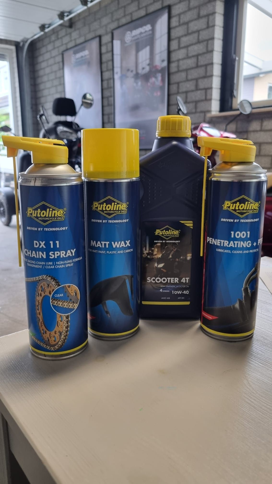 Diverse blauw-gouden flessen en spuitbussen op een tafel buiten voor een huis.