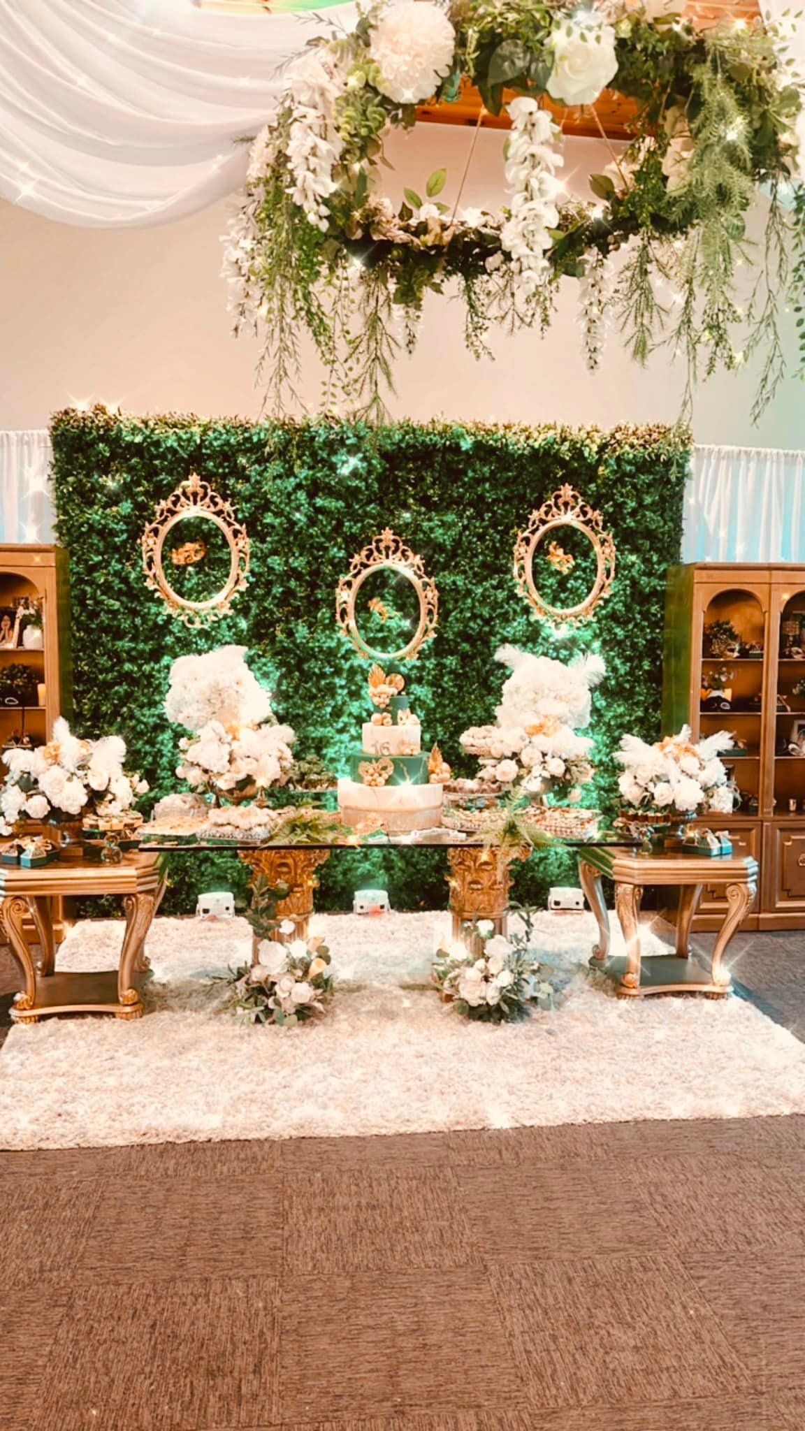 There is a table with flowers on it in front of a green wall.