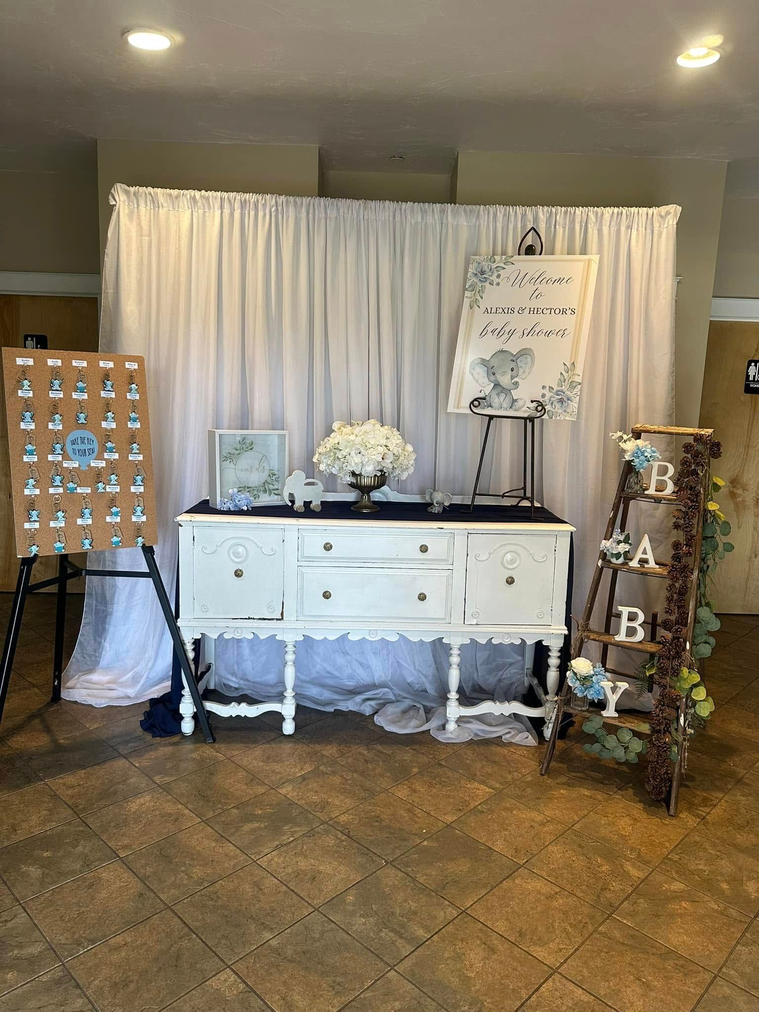 A white dresser is sitting in front of a white curtain in a room.