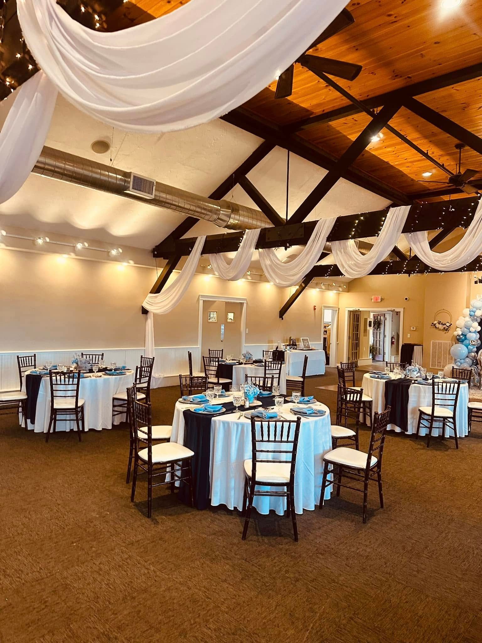 A large room with tables and chairs set up for a wedding reception.