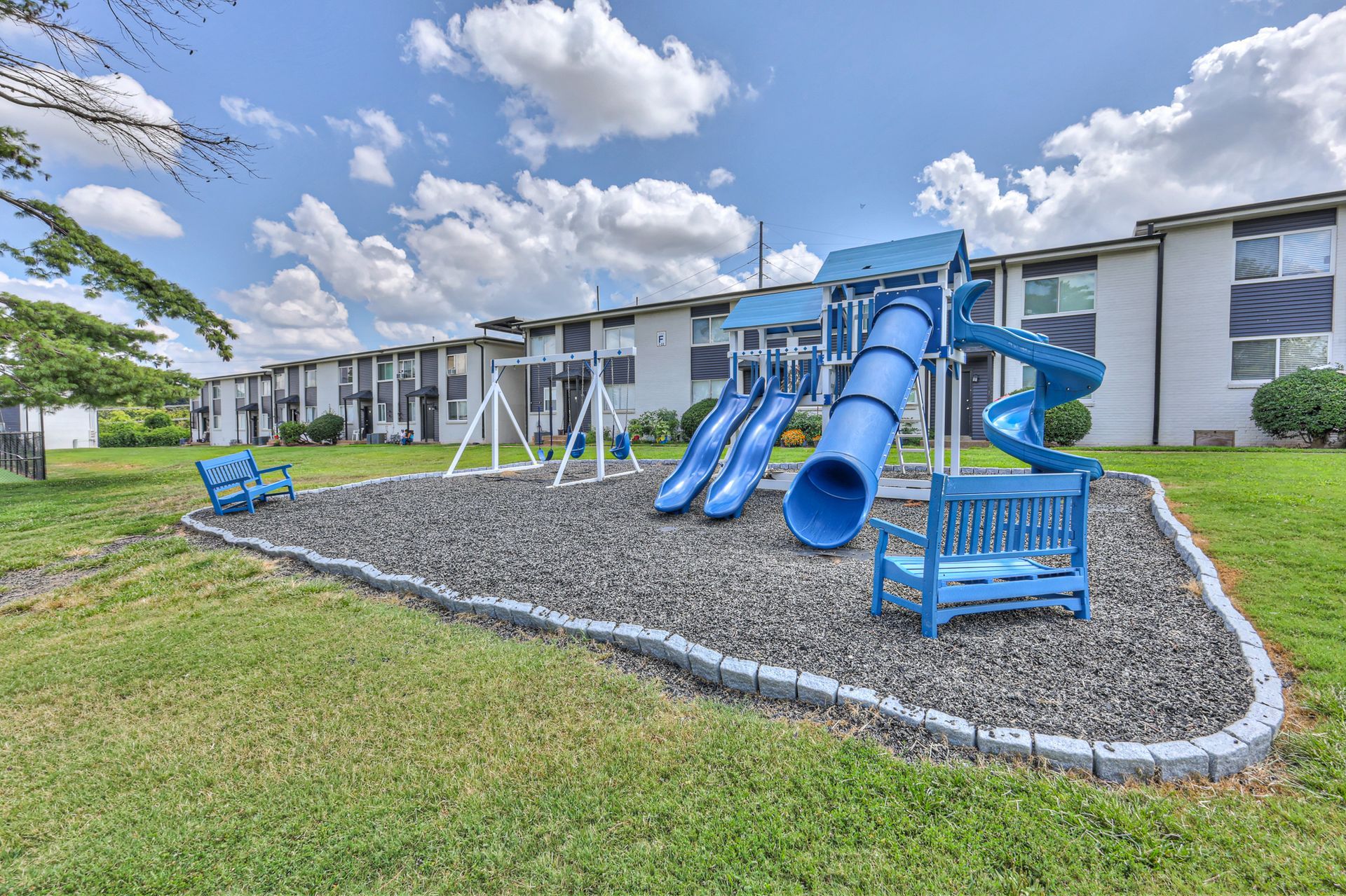 Photo of a comunity playground with benches, swings and slides