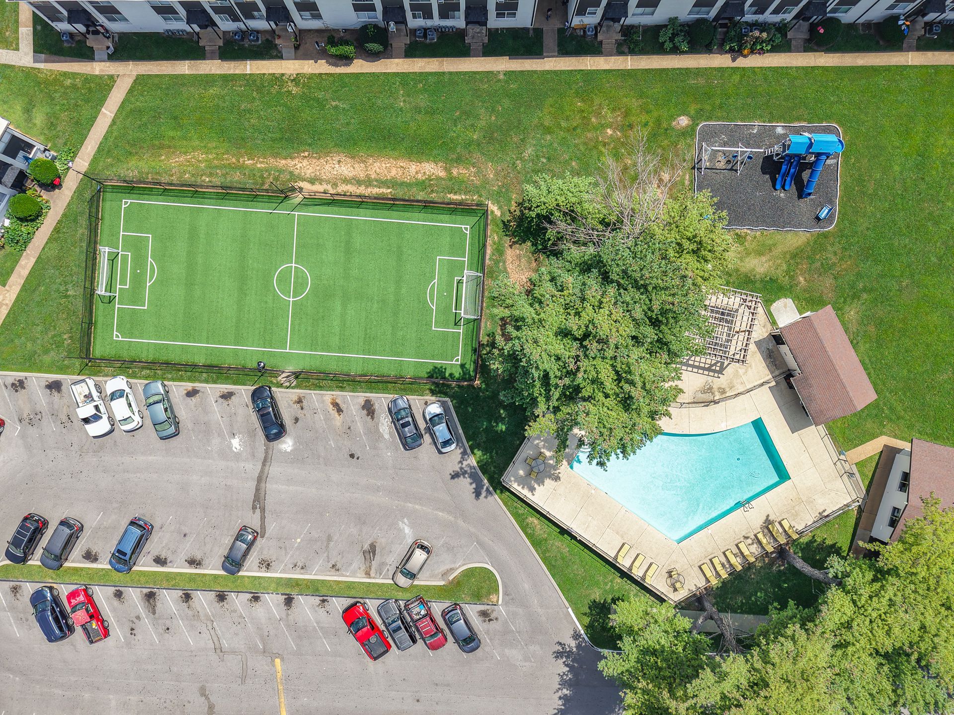 Aerial photo of the community playground, soccer field and pool, with one of the buildings at the edge of the photo