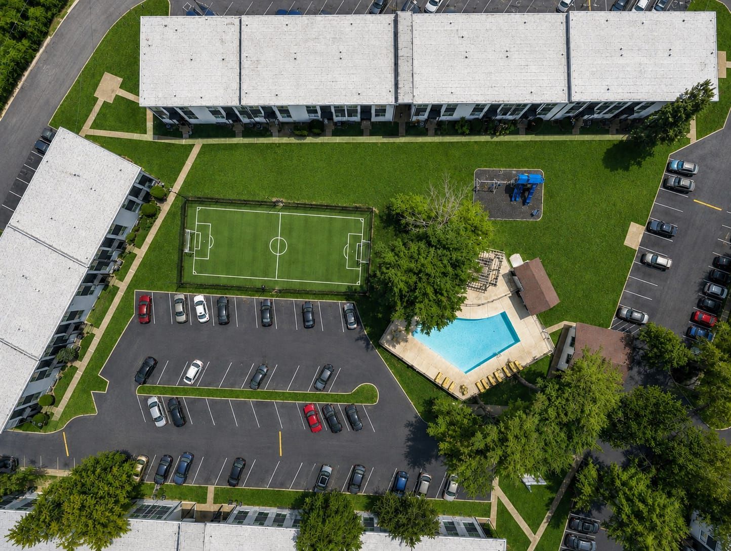 Aerial photo of the community playground, soccer field and pool, with one of the buildings at the edge of the photo