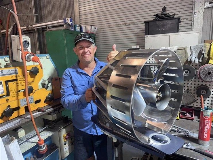 Man in blue shirt holding a large metal industrial drum in a workshop Man in blue shirt holding a large metal industrial drum in a workshop