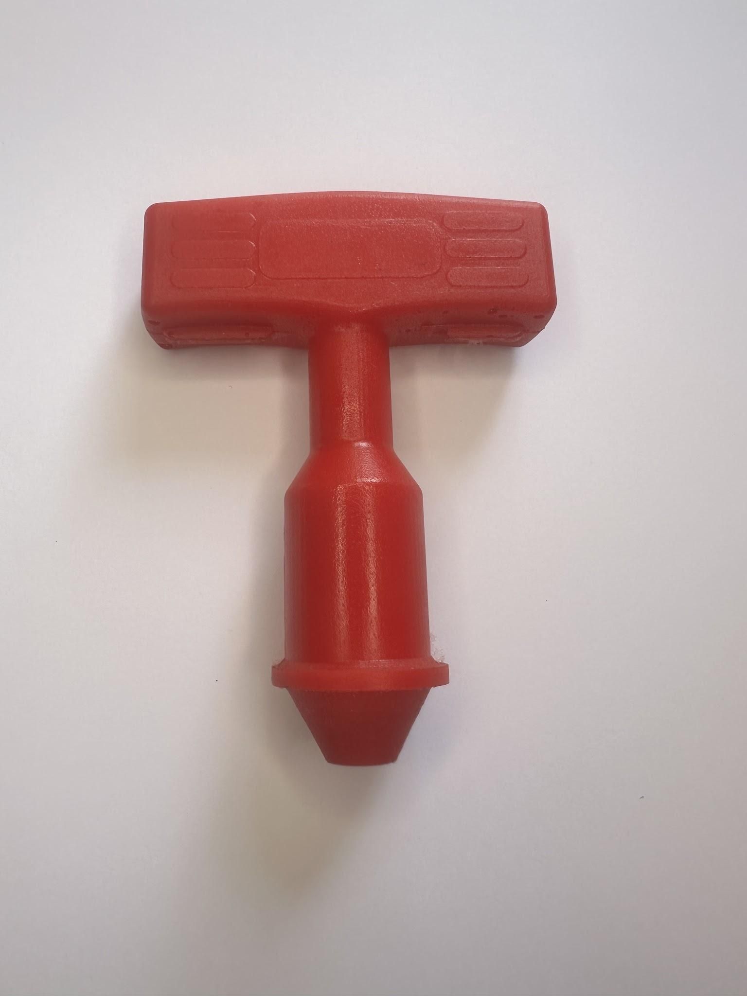 Red plastic T-shaped connector or tool on a white background