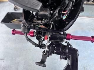 Close-up of a motorcycle’s front suspension and handlebars with red components in a workshop.